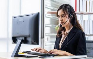 call center, consulente del service desk che parla al telefono vivavoce, donna d'affari del call center che parla con l'auricolare, donna nella posizione del servizio clienti che parla al telefono, concetto di ufficio e business foto