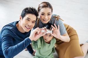 famiglia felice, piccola figlia asiatica che gioca a puzzle con sua madre e suo padre per il concetto di famiglia, assemblano puzzle. foto