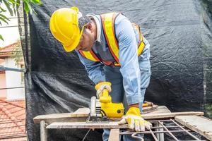 falegname con sega circolare per il taglio di tavole di legno con utensili elettrici, costruzione e ristrutturazione casa, riparazione e strumento di costruzione foto