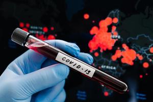 la mano in guanti medici di gomma tiene la provetta contenente il campione dei pazienti contro la mappa di covid-19. test sul coronavirus. concetto di analisi del sangue. situazione pandemica foto