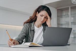 la signora spagnola oberata di lavoro ha mal di testa. il libero professionista stanco malato sta lavorando sul laptop a casa. foto