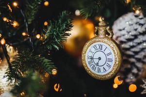 foto di capodanno decorato o albero di natale con ghirlande e palline. la decorazione a forma di orologio simboleggia l'inizio del nuovo anno. vacanze, celebrazione, concetto invernale.