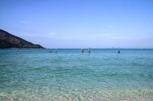 mare tropicale cristallino con poli e cielo blu foto