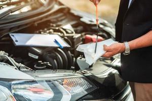 meccanico che ripara l'auto con il cofano aperto, vista laterale del meccanico che controlla il livello dell'olio motore in un'auto con il cofano aperto foto