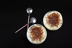 budino di latte dolce con mandorle e gocce di cioccolato isolato su sfondo scuro foto