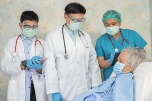 il team di medici asiatici controlla la vecchia paziente anziana per la malattia alla motivazione nuova normalità per il trattamento dell'infezione covid-19 coronavirus nel reparto ospedaliero. foto