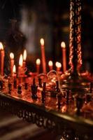molte candele accese di notte in chiesa. gruppo di candele accese al buio. avvicinamento. copia spazio. foto
