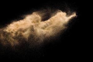 esplosione di sabbia di fiume secca. spruzzata di sabbia color oro su sfondo scuro. foto