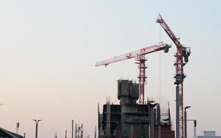 sfondo industriale astratto con sagome di gru edili su un fantastico cielo al tramonto foto