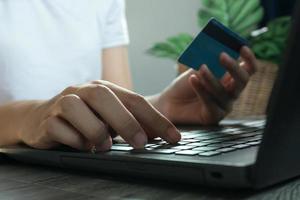 mani che tengono la carta di credito e utilizzano il laptop. acquisti online. concetto di lavoro da casa foto