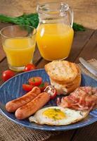colazione all'inglese - pane tostato, uova, pancetta e verdure in stile rustico su fondo di legno foto