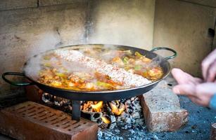 cucinare e preparare una tradizionale paella spagnola sul fuoco aperto