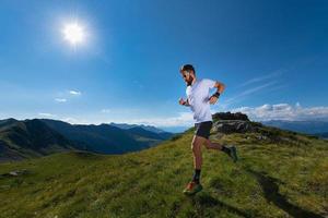 atleta uomo che pratica la corsa in montagna al sole ad alta quota foto