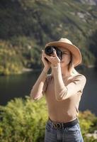 fotografo turista viaggiatore in piedi sulla cima verde sulla montagna tenendo in mano la fotocamera digitale foto