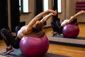 giovane donna in abbigliamento sportivo è impegnata su fitball in palestra al coperto foto