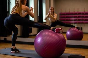 giovane donna in abbigliamento sportivo è impegnata su fitball in palestra al coperto foto