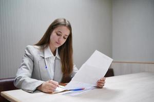 giovane imprenditrice sul posto di lavoro e leggere la carta in ufficio foto