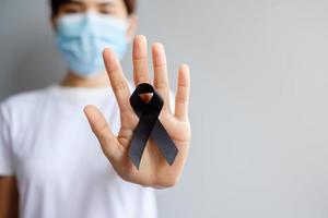 donna con nastro nero per melanoma e cancro della pelle, mese di sensibilizzazione sulle lesioni da vaccino, dolore e riposo in pace. concetto di assistenza sanitaria e razzista foto