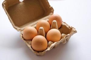 uova nel vassoio delle uova di carta su sfondo bianco. foto