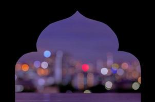 carta nera tagliata a forma di moschea con luce bokeh colorata della città foto