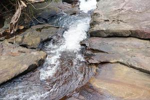 l'acqua nel ruscello scorre attraverso le lastre di pietra. foto