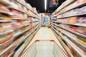 Sfocatura movimento del corridoio del supermercato con carrello vuoto foto