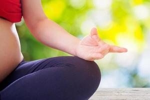 donna incinta che fa yoga con il fondo del bokeh della natura foto