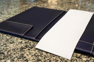 carta bianca vuota in bianco nella cartella della ricevuta di fatturazione del pagamento del ristorante sul tavolo di granito foto