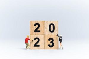 artista di graffiti di persone in miniatura che spruzza il numero 2023 su un blocco di legno foto