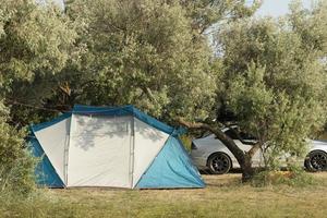 viaggiando in auto con una tenda turistica sullo sfondo di alberi verdi. foto