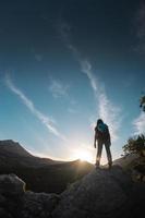 la silhouette di una donna con uno zaino sullo sfondo di una montagna al tramonto foto