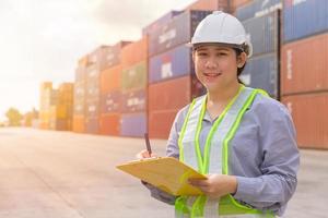 asiatico giovane adolescente felice lavoratore che controlla le scorte nel porto di spedizione il lavoro gestisce i contenitori di carico per l'importazione e l'esportazione. foto