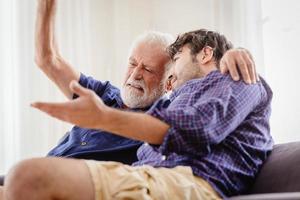 discussione seria del vecchio con l'uomo più giovane al chiuso, nonno serio che parla con suo figlio a casa. foto