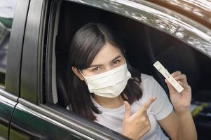 una donna che tiene in macchina, fa un test di auto-raccolta per un test covid-19, salute e sicurezza foto