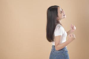 un ritratto di donna asiatica con t-shirt bianca su sfondo marrone chiaro studio foto