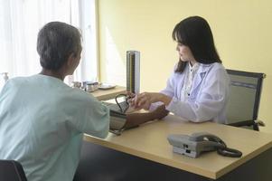 il paziente maschio anziano asiatico sta consultando e visitando il medico in ospedale.. foto