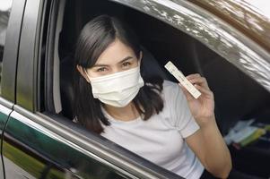 una donna che tiene in macchina, fa un test di auto-raccolta per un test covid-19, salute e sicurezza foto