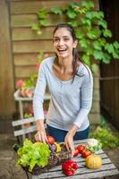 donna con verdure in un cestino al tavolo del giardino