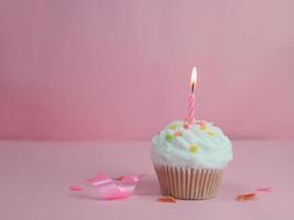 Cupcake di buon compleanno e candela di prua su sfondo rosa con spazio per la copia. foto