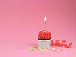 dolce cupcake rosso con fiocco candela su sfondo rosa con copia spazio. concetto di sfondo festa di buon compleanno. foto