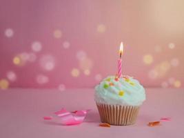 Cupcake di buon compleanno e candela di prua su sfondo rosa con spazio per la copia. foto