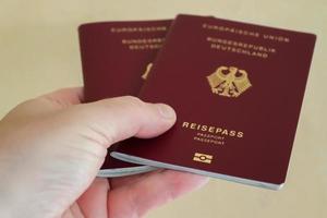 una mano maschile tiene due passaporti tedeschi per il controllo passaporti. foto