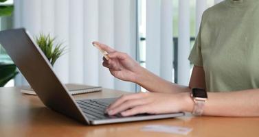 acquisti online. giovane donna in possesso di carta di credito e utilizzando il laptop a casa. ragazza afroamericana che lavora al computer al bar. affari, e-commerce, internet banking, finanza, concetto di freelance foto