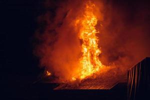 casa in fiamme di notte. forte incendio in un piccolo villaggio foto