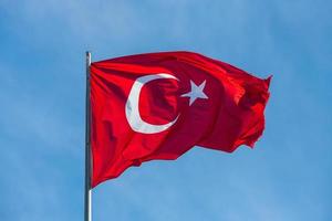 bandiera nazionale della turchia su un pennone che sventola contro un cielo blu foto