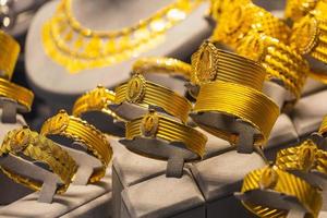 vetrina di una gioielleria con una vasta selezione di bracciali, catene, anelli e orecchini di gioielli in oro su rilievo femminile foto