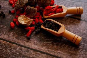 vista dall'alto dell'ingrediente del cibo asiatico, del fungo shitake essiccato, del pepe nero e delle bacche di lupo cinesi essiccate o dell'erba cinese della bacca di goji in una paletta di legno su fondo di legno. concetto sano asiatico. foto