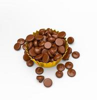 vista dall'alto gocce di cioccolato che cadono in una tazza di carta dorata su sfondo bianco isolato illustrazione 3d foto