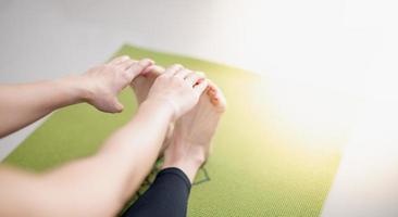 donna che fa yoga sul tappetino yoga verde per meditare ed esercitarsi in casa. foto