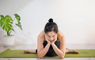 donna che fa yoga sul tappetino da yoga verde per meditare ed esercitarsi in casa. foto